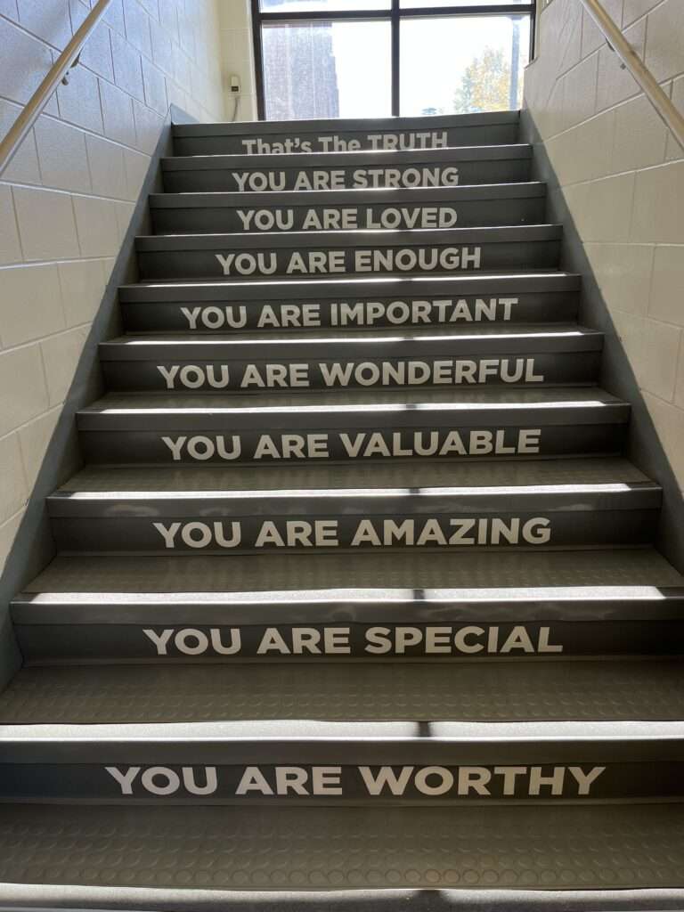 Stairs in a hospital that have sayings on each step. From the bottom up the steps read: "You are worthy, you are special, you are amazing, your are valuable, you are wonderful, you are important, your are enough, you are loved, you are strong, that's the truth"