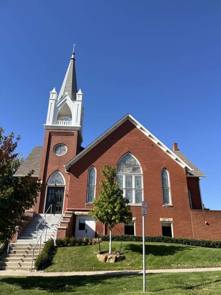Image of brick church building with white trim and a tall steeple.